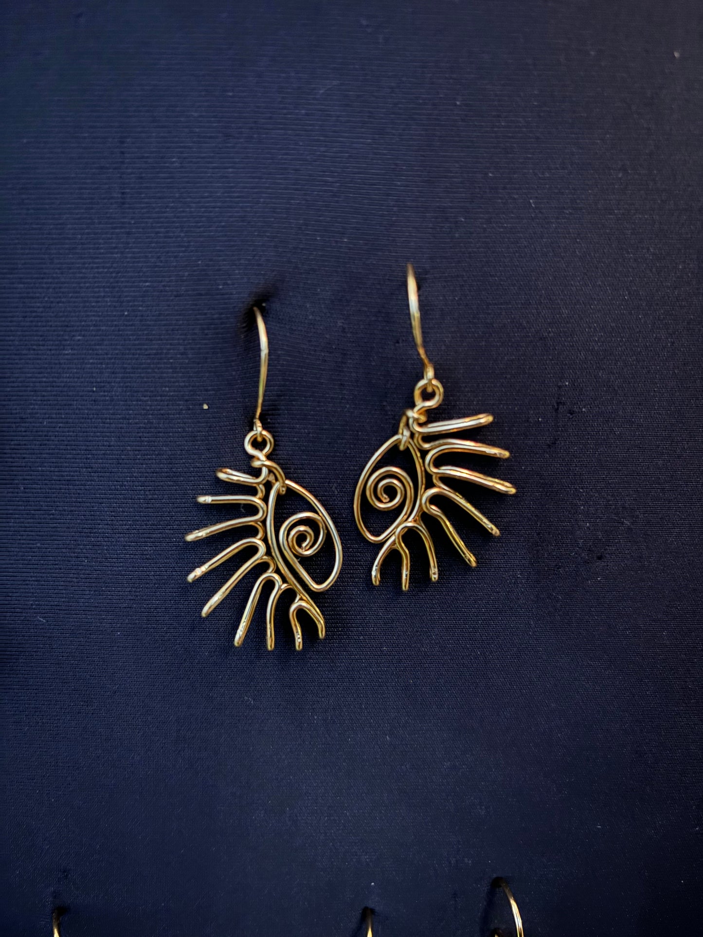 Présentation de boucles d’oreilles en acier inoxydable 316L motif œil sur un fond noir raffiné.