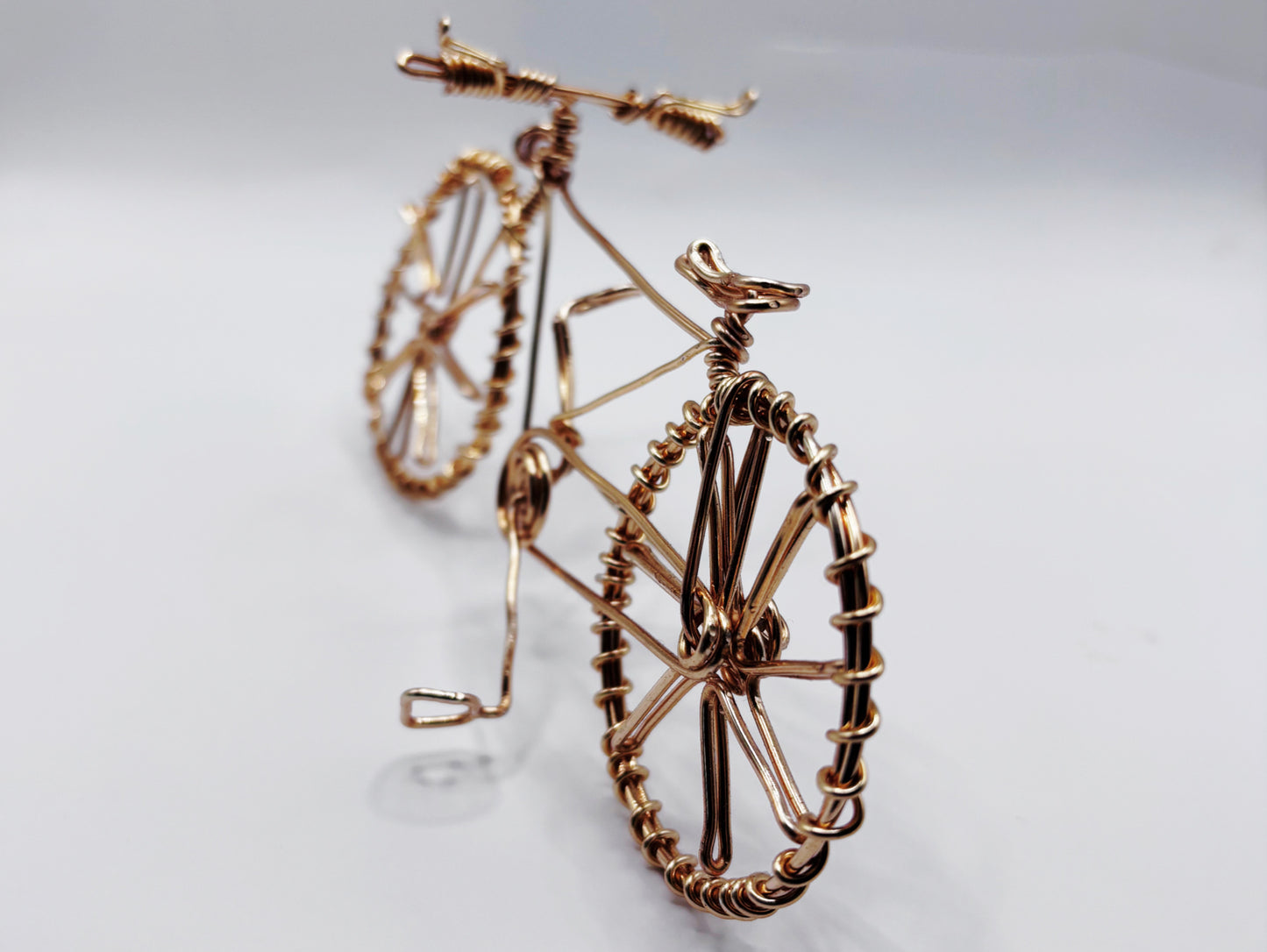 Vue rapprochée d’un vélo en fil de laiton doré, une pièce artistique unique et élégante.