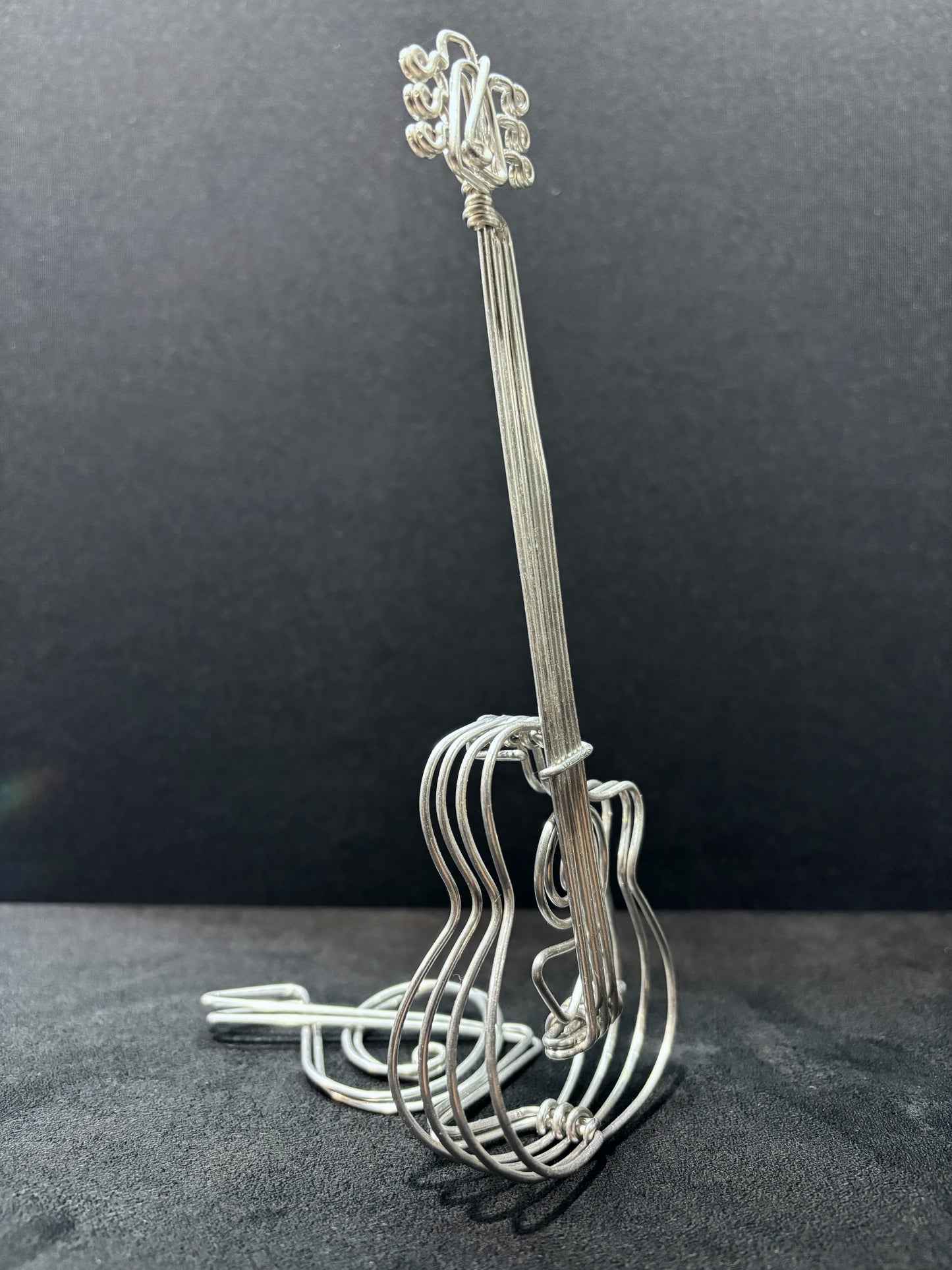 Création artistique en aluminium en forme de guitare, avec des courbes harmonieuses et un style minimaliste.