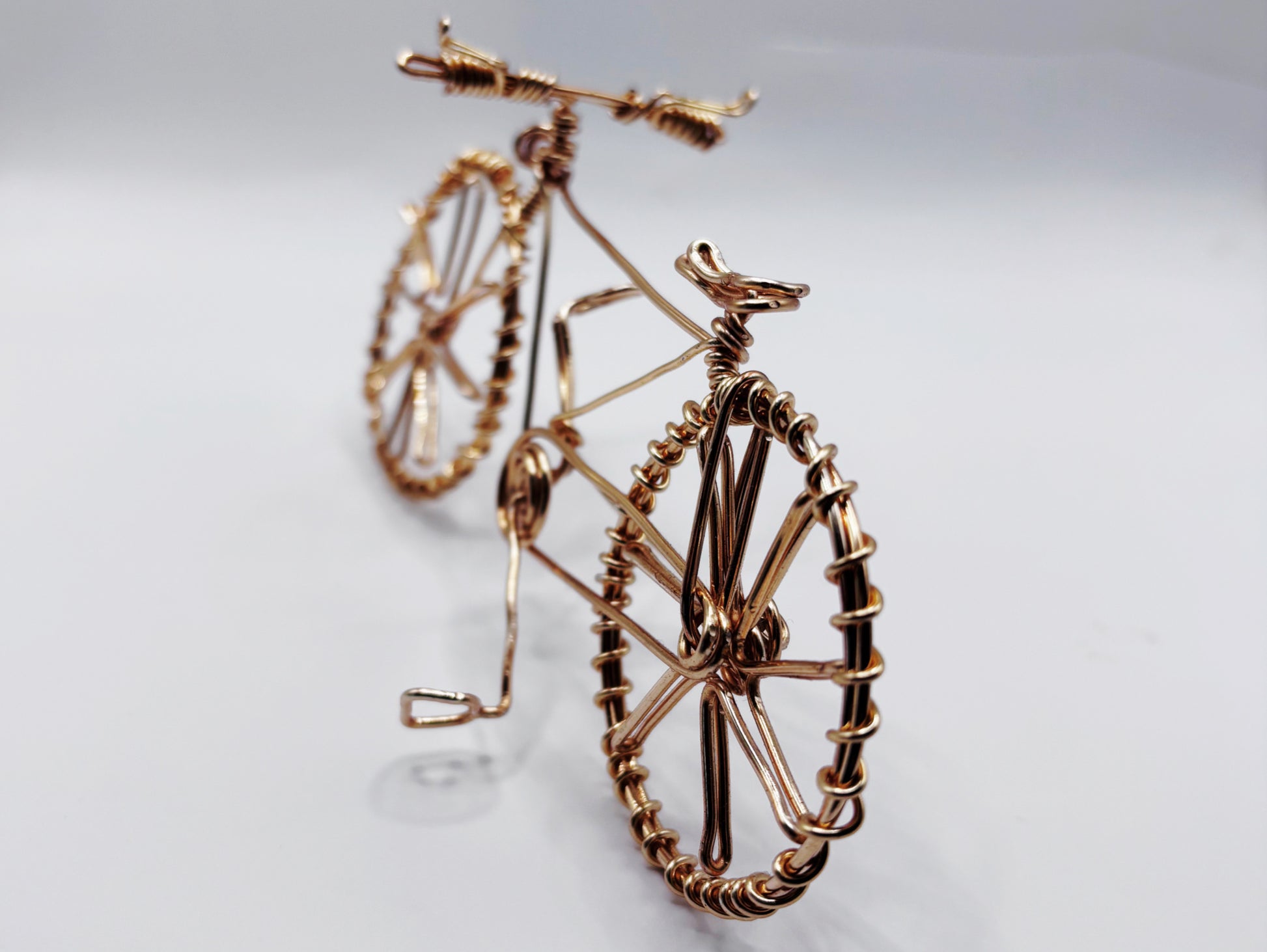 Vue rapprochée d’un vélo en fil de laiton doré, une pièce artistique unique et élégante.