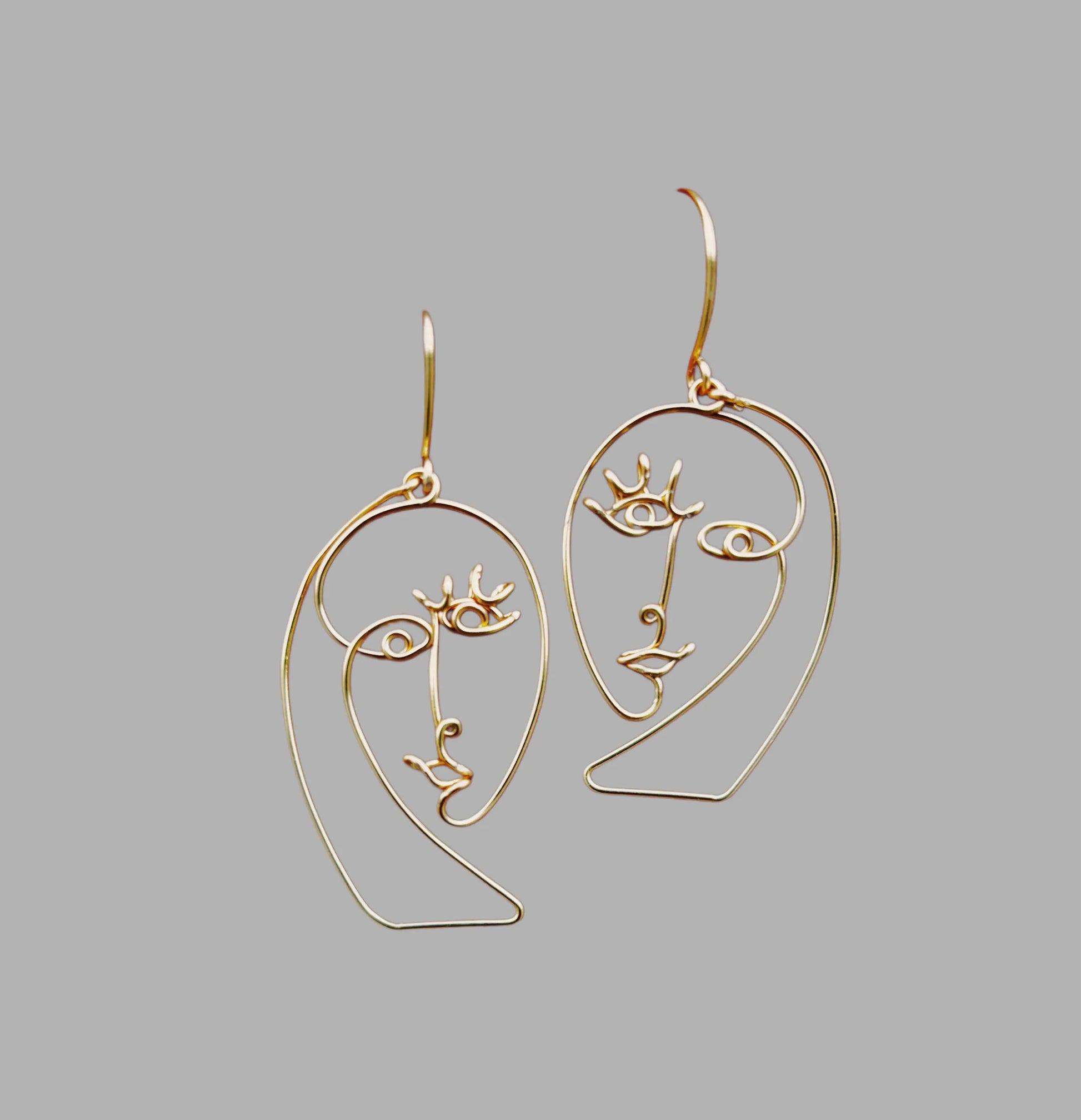 Boucles d’oreilles contemporaines en fil, bijou fait main, présentation minimaliste haut de gamme.