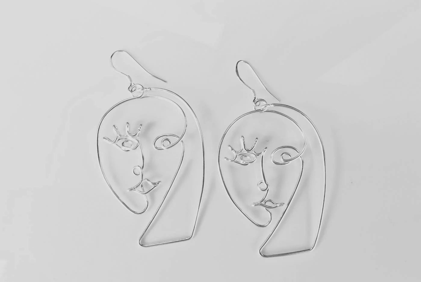 Boucles d’oreilles en fil design moderne, présentation soignée, style galerie de luxe.