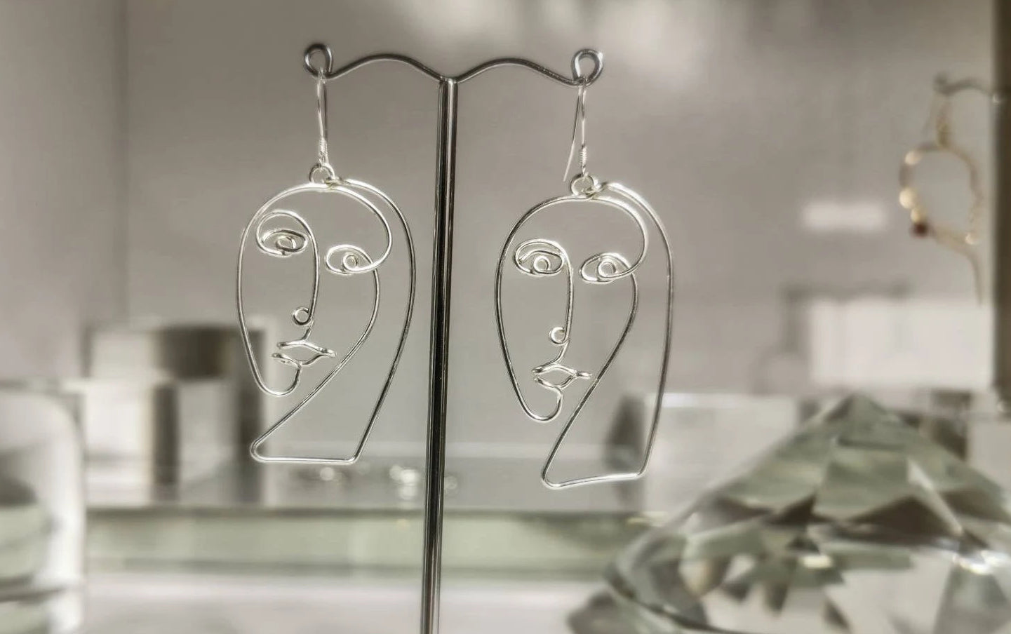 Boucles d’oreilles abstraites faites main, exposition sur présentoir élégant, esthétique premium.