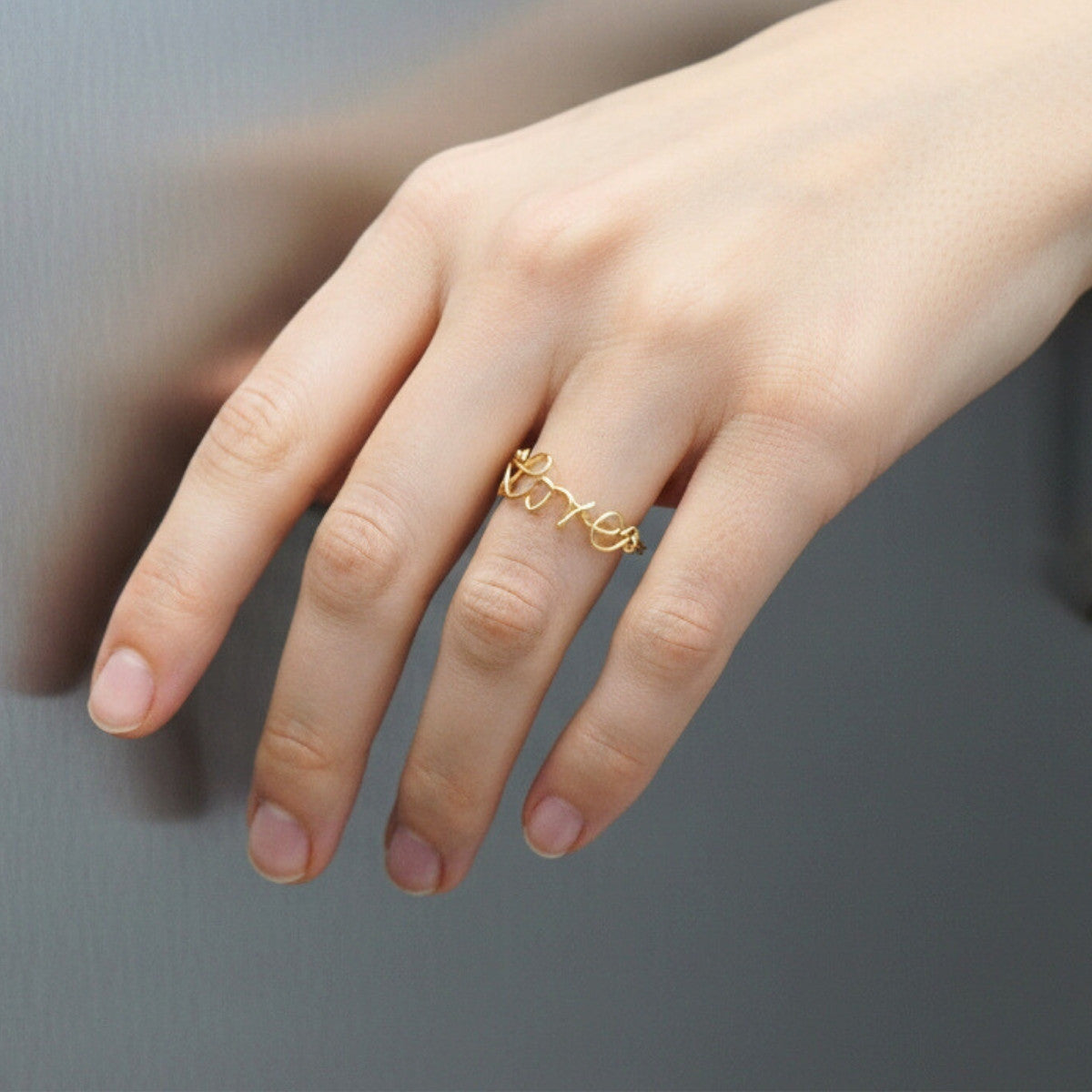Bague prénom en or portée sur une main féminine, bijou fin et intemporel