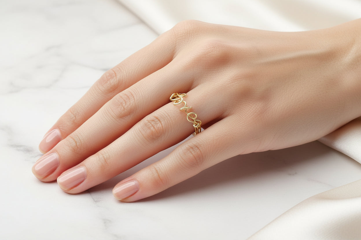 Bague prénom personnalisée en fil doré, bijou fait main porté sur la main d’une femme.