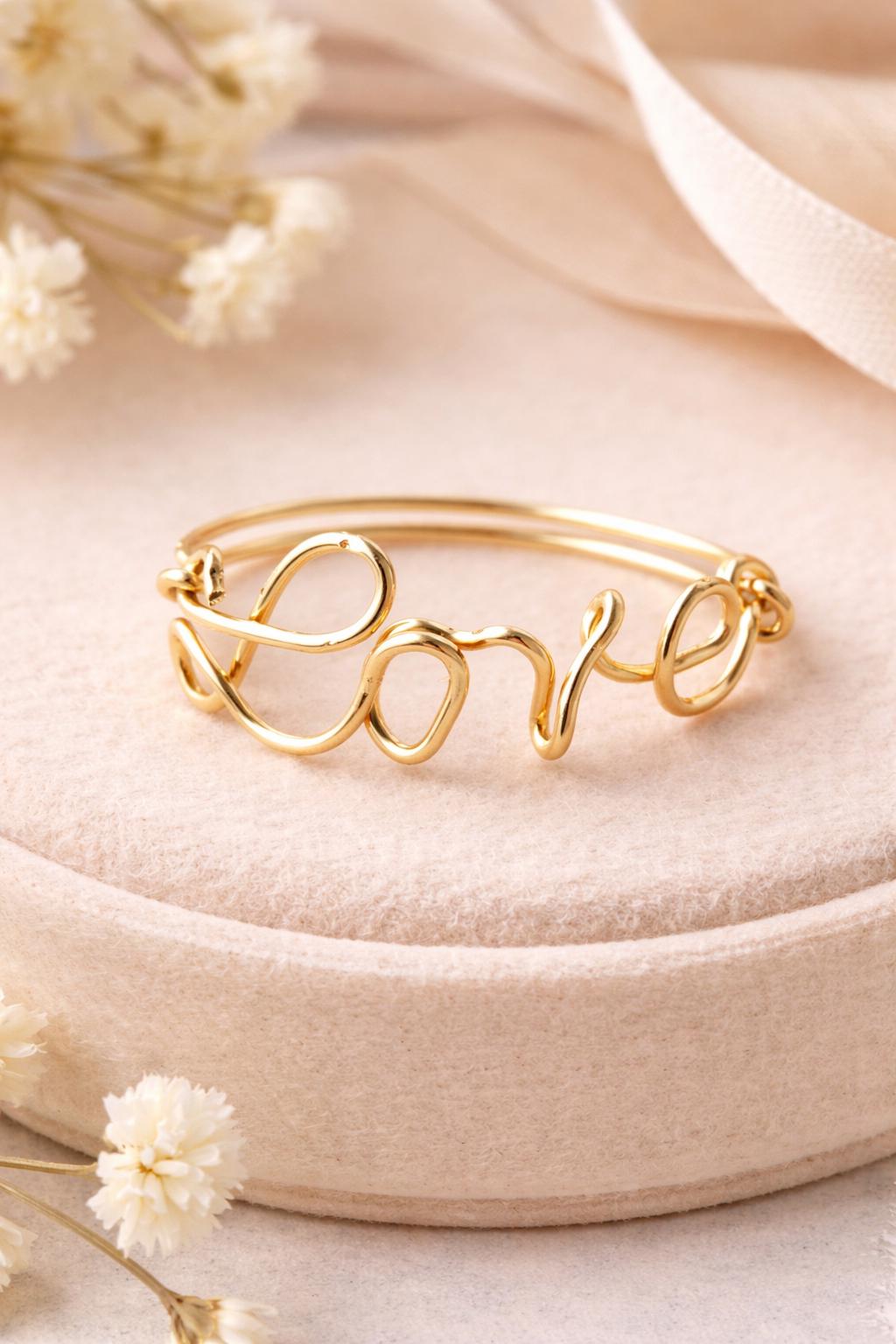 Bague prénom personnalisée en fil doré, présentée sur un support élégant au style luxe.