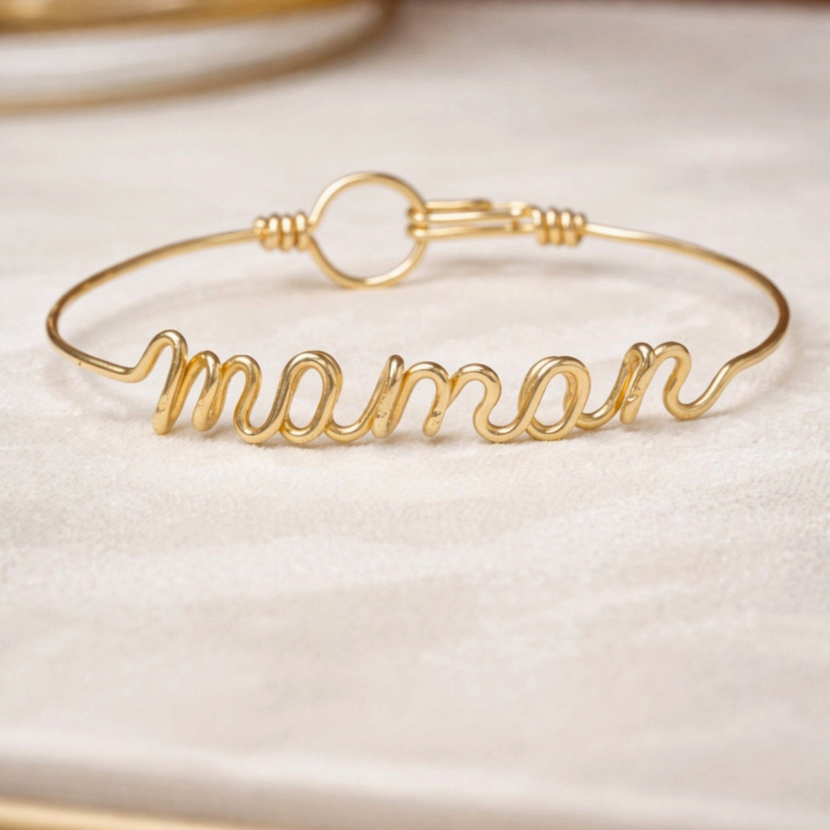 Bracelet prénom en or personnalisé présenté sur une surface claire, bijou fin