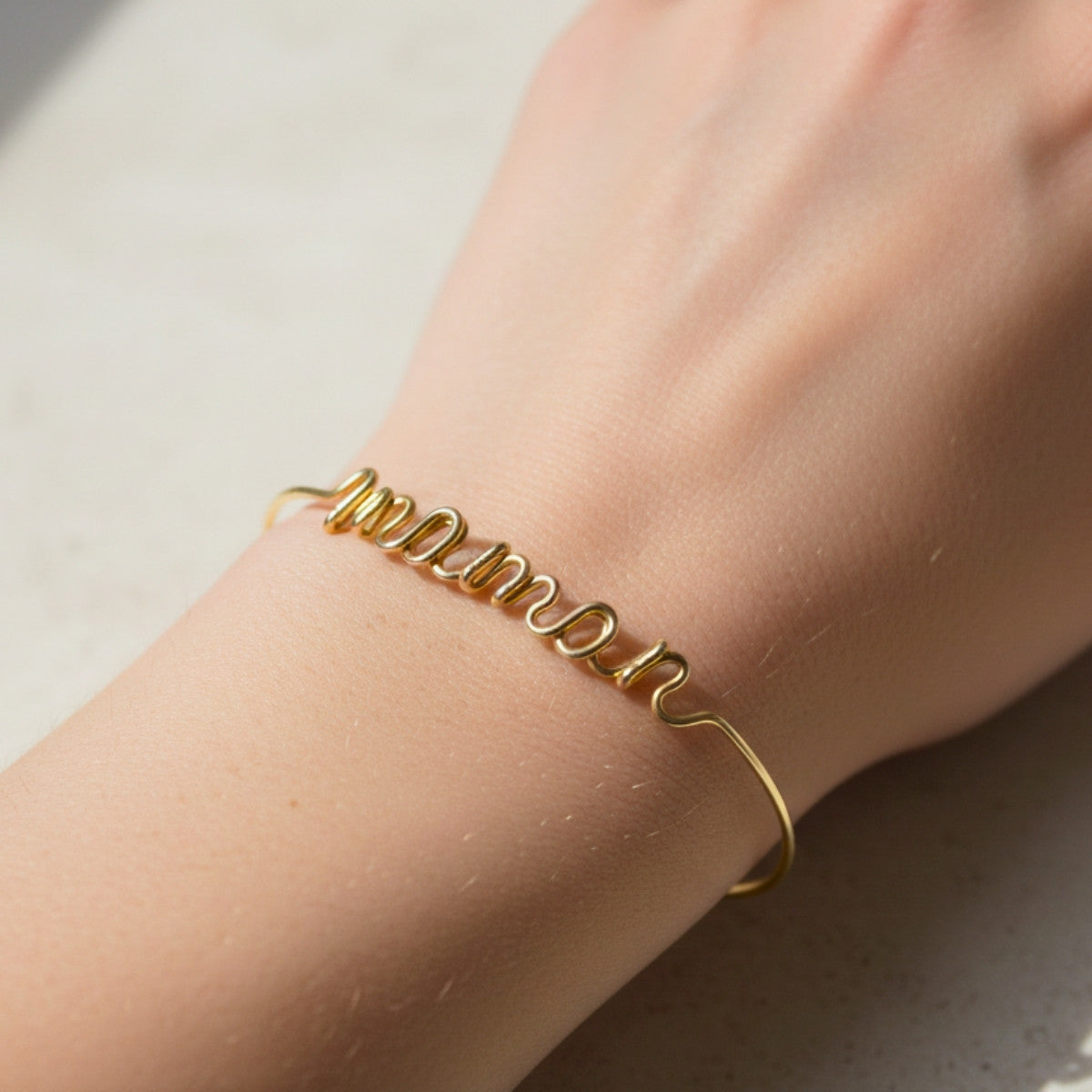 Bracelet prénom en or personnalisé porté au poignet d’une femme, bijou délicat