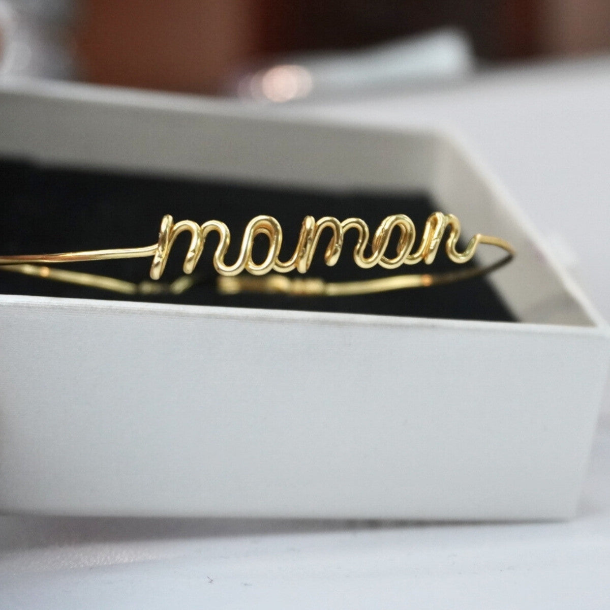 Bracelet prénom en or personnalisé posé sur un tissu, bijou délicat et raffiné