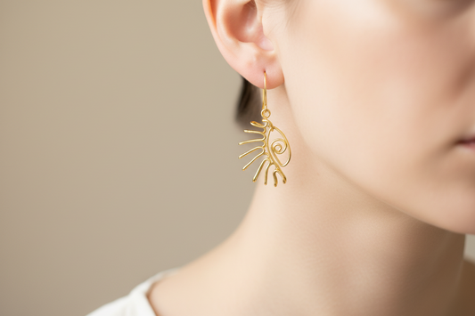 Boucles d’oreilles minimalistes en fil doré, exposées sur un présentoir de luxe avec écrin Najdovski.