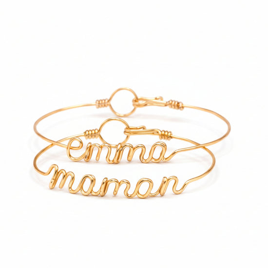 Bracelet prénom personnalisé en fil doré, façonné à la main, présenté dans un coffret cadeau avec ruban blanc.