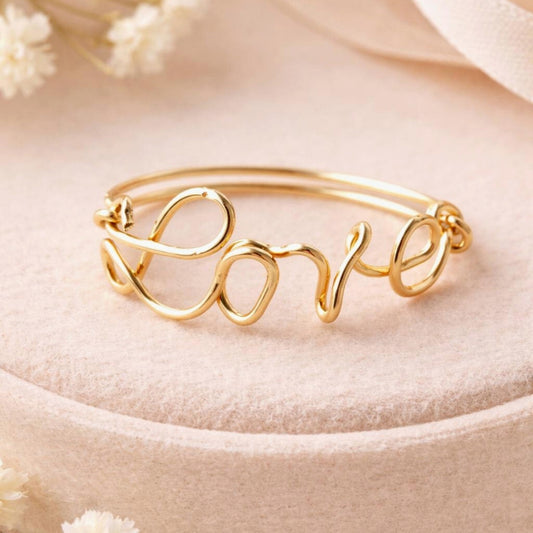 Bague prénom personnalisée en or posée sur un présentoir rose