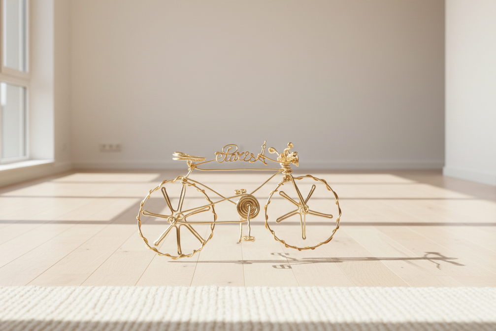Sculpture de vélo en fil doré faite à la main, exposée dans une galerie moderne au style élégant.
